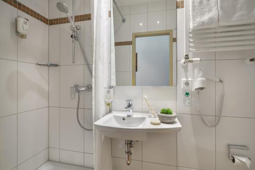 a white bathroom with a sink and a shower at Novum Hotel Graf Moltke Hamburg in Hamburg