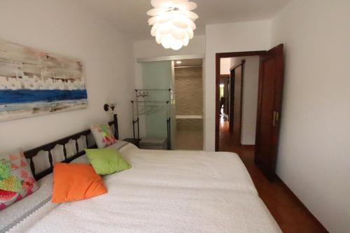 een slaapkamer met een groot wit bed met kleurrijke kussens bij Planta baja, primera linea, playa, jardín privado, Ardiaca, Cambrils, apartamento Jacqueline in Cambrils