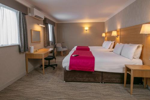 a hotel room with a large bed and a desk at Best Western Heath Court Hotel in Newmarket