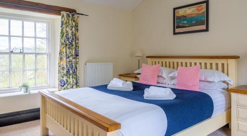 a bedroom with a large bed with pink and white pillows at Hilltop in Far Sawrey