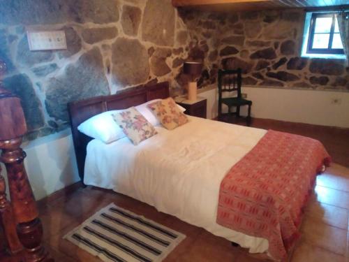 - une chambre avec un lit et un mur en pierre dans l'établissement 5 bedrooms property with private pool and wifi at Nande 5 km away from the beach, à Donas