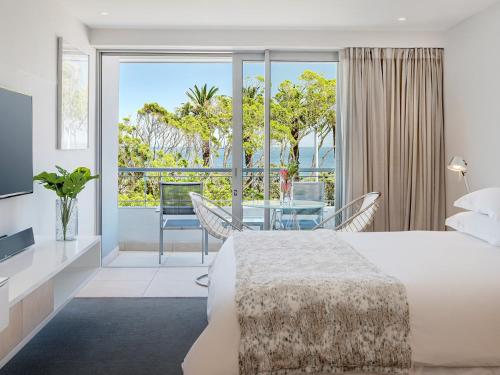 a bedroom with a bed and a dining room with a view at South Beach Camps Bay Boutique Hotel in Cape Town