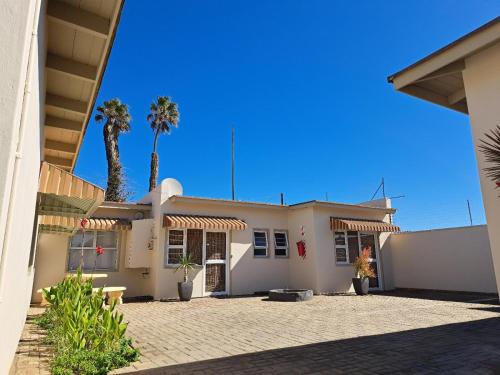 une maison blanche avec un palmier en arrière-plan dans l'établissement Bushbabies-Inn Self-Catering Accommodation, à Swakopmund