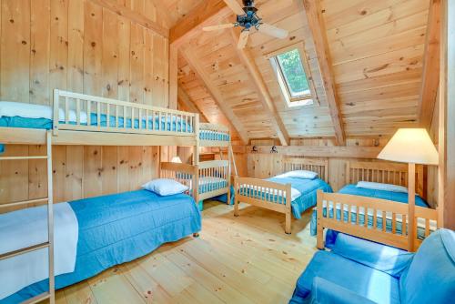 Dormitorio en cabaña de madera con 2 literas y sofá en Lakefront Westhampton Cabin with Beach and Kayaks!, en Westhampton