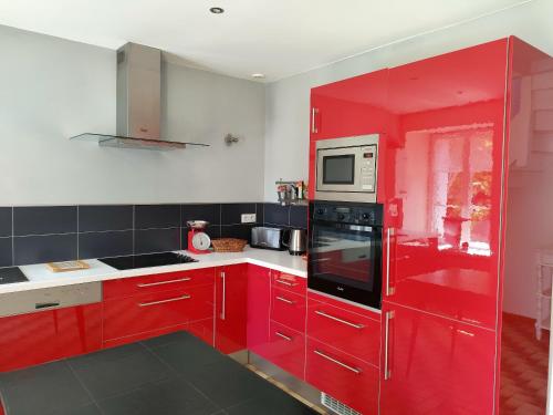 une cuisine avec des armoires rouges et un micro-ondes dans l'établissement Maison de charme au Vivier-sur-Mer avec terrasse privée, au Vivier-sur-Mer