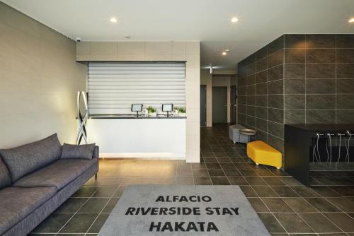 ALFACIO RIVERSIDE STAY HAKATA في فوكوكا: غرفة معيشة مع أريكة ومدفأة