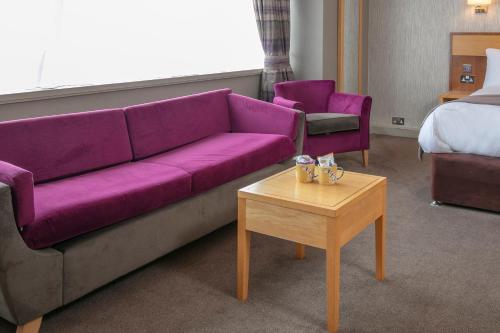 a living room with a purple couch and a table at Best Western Heath Court Hotel in Newmarket