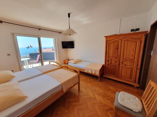 a bedroom with two beds and a large window at Apartmani Miljak Omiš in Omiš