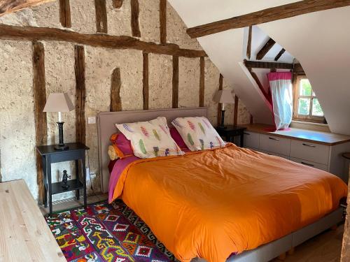 a bedroom with a bed with an orange blanket at Le grand Moulin in Pernay