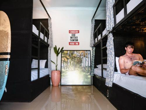 a room with two bunk beds with a man sitting on them at Clandestino Hostel Canggu in Canggu