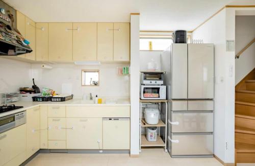 a kitchen with white cabinets and a refrigerator at Private lodging in WEST TOKYO(SHINJUKU, TACHIKAWA, SANRIO, GHIBLI, MT. TAKAO etc) in Kokubunji