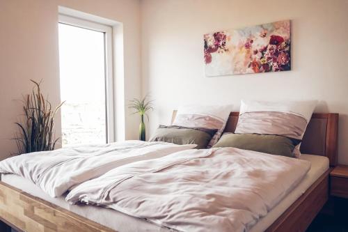 Schlafzimmer mit einem Bett mit weißer Bettwäsche und einem Fenster in der Unterkunft FEWO Morgenröte - Weserblick -Harriersand in Schwanewede
