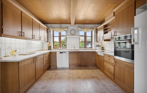 a large kitchen with wooden cabinets and a window at Lovely Home In Skærbæk in Skærbæk