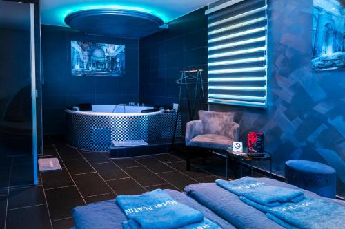 Baño azul con bañera y silla en Hotel Platin en Regensburg