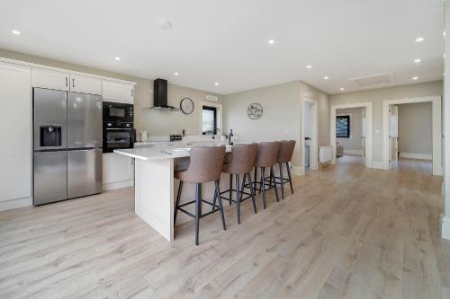 a kitchen with white cabinets and bar stools at Seaview Lodge Apartment 'Sleeping 4 Guests' in Tieveborne