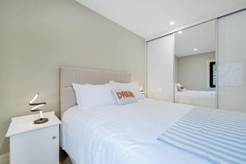 a white bedroom with a white bed and a mirror at Seaview Lodge Apartment 'Sleeping 4 Guests' in Tieveborne