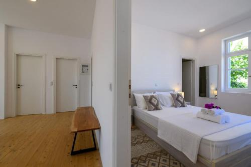 a white bedroom with a bed and a window at Katina's Coastal Oasis in Pylos