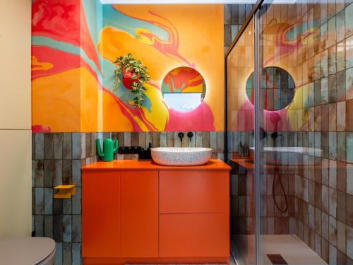 an orange bathroom with a painting on the wall at Downtown Apartments Chlebova Riverside - Parking & Gym in Gdańsk