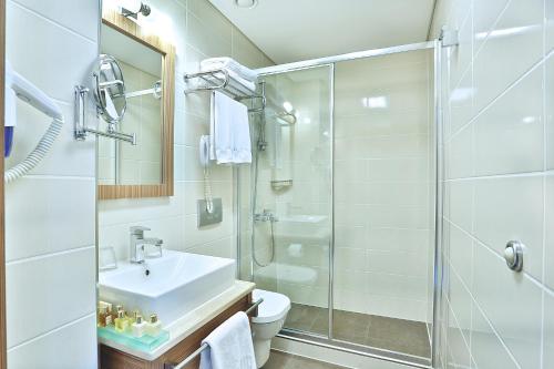 La salle de bains blanche est pourvue d'un lavabo et d'une douche. dans l'établissement Hotel Momento - Special Category, à Istanbul