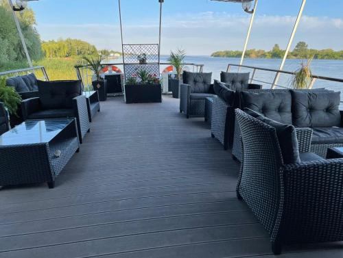 a deck with chairs and tables and a view of the water at Hotel Plutitor Egreta1 in Sfântu Gheorghe