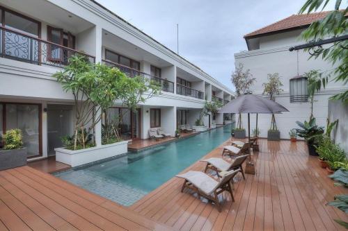a swimming pool in a building with chairs and an umbrella at Seminyak Lagoon All Suites Hotel in Seminyak