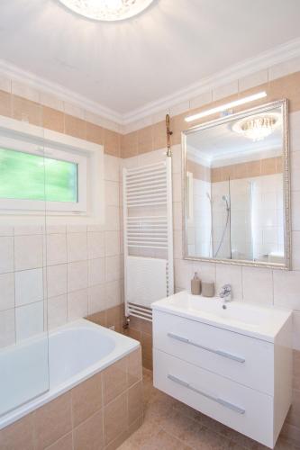 a bathroom with a tub and a sink and a mirror at Panorama Residence in Balatonalmádi