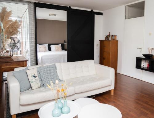 a living room with a white couch and a bed at Center Appartement Apeldoorn in Apeldoorn
