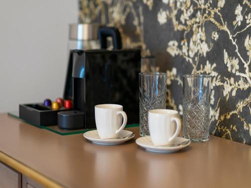 a counter with two cups and two glasses on it at Sia Boutique Aparthotel in Sibiu
