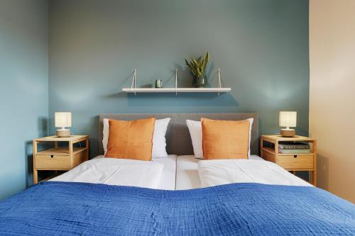 a bedroom with two beds with blue walls and orange pillows at homie stay Badgasse - Fewos am Main mit Dachterrasse & Fahrradgarage in Ochsenfurt
