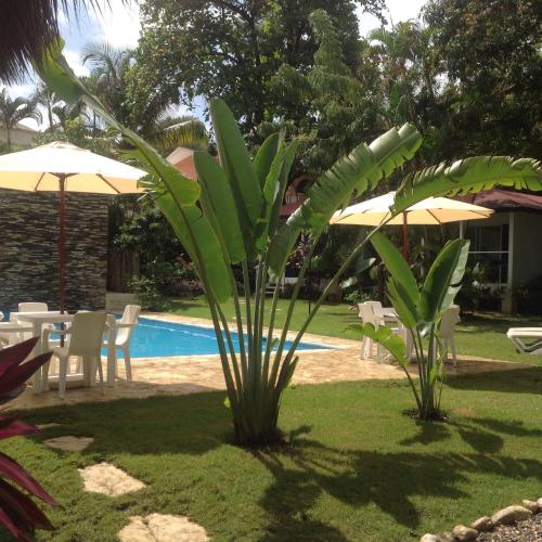 a pool with tables and chairs and umbrellas at Bungalow Natura Village in Sosúa