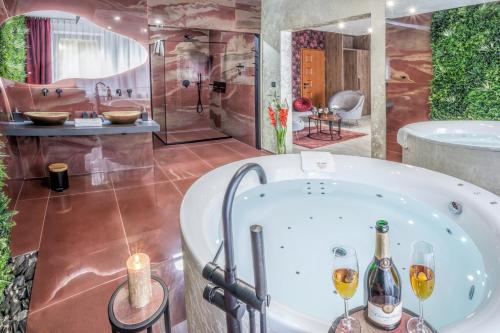 a bathroom with a tub and two glasses of champagne at Hotel Beta in Bzenec