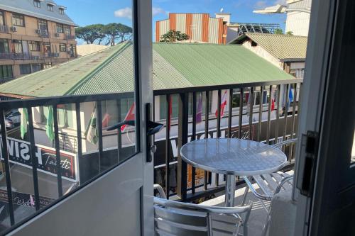 a table and chairs on the balcony of a building at "Hibiscus" city center room in Papeete