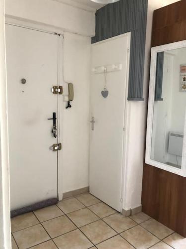 La salle de bains est pourvue de deux portes blanches et d'un miroir. dans l'établissement Appartement balcon, place de parking, centre ville, à Valence