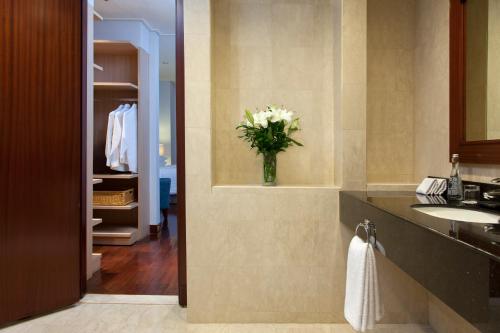a bathroom with a sink and a vase of flowers at The Mayflower, Jakarta-Marriott Executive Apartments in Jakarta