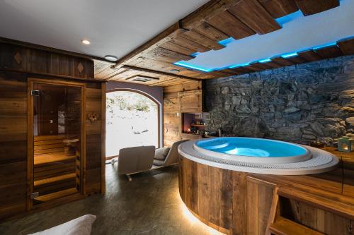 bañera de hidromasaje en una habitación con pared de piedra en Le Moulin Des Aravis en Pontboset
