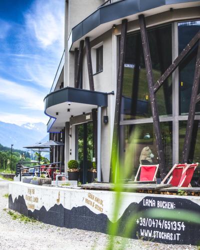 a building with red chairs outside of it at Gourmet AlpinHotel Sonnleiten in Cadipietra