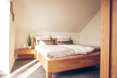 um quarto com uma cama de madeira com lençóis e almofadas brancos em Ferienwohnung Sonnenuntergangsidyll Harriersand em Schwanewede