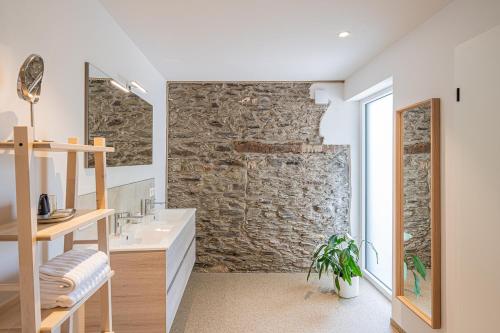 uma casa de banho com uma parede de pedra e um lavatório em B&B - La Maison des Sottais em Burg-Reuland