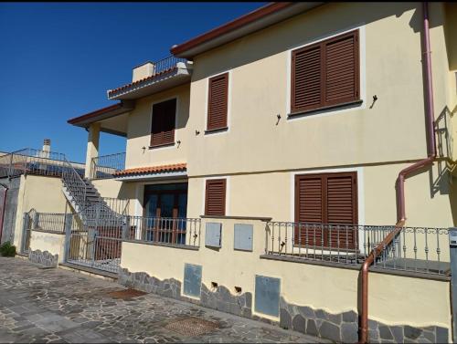 Casa blanca con persianas marrones y escaleras en Appartamento Stelle e Coralli, en Tresnuraghes