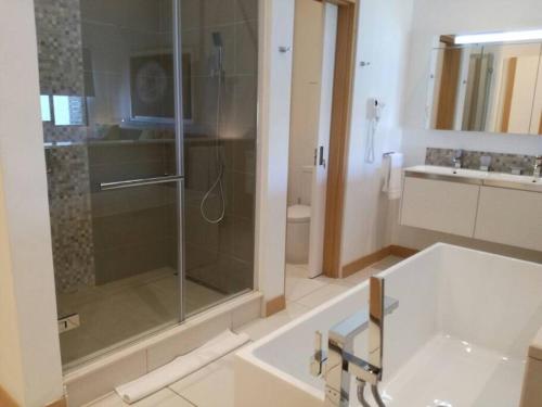 La salle de bains est pourvue d'une douche en verre et d'un lavabo. dans l'établissement Latitude Sea Front Luxury Apartment, à Rivière Noire