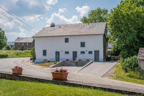 a white house with two flower pots in front of it at B&B - La Maison des Sottais in Burg-Reuland