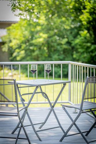 a table with two glasses of wine sitting next to two chairs at B&B - La Maison des Sottais in Burg-Reuland
