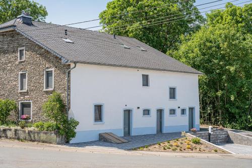 a white building with blue doors on a street at B&B - La Maison des Sottais in Burg-Reuland