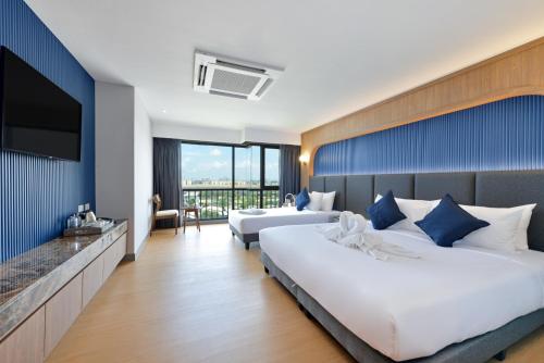 a hotel room with two beds and a flat screen tv at VST Residence -SHA PLUS Certified in Ban Khlong Bang Ping