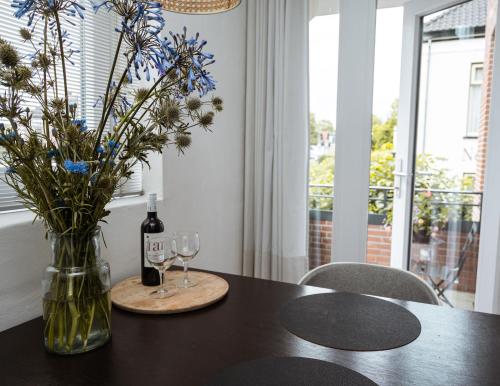 einen Tisch mit einer Vase Blumen und einer Flasche Wein in der Unterkunft Center Appartement Apeldoorn in Apeldoorn