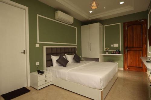 a bedroom with a large bed with green walls at White Mint in Yercaud