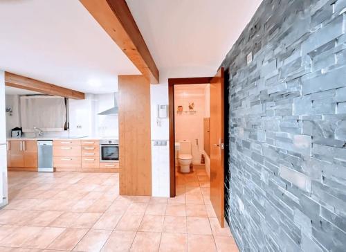 a kitchen with a stone wall and a toilet at Casa de vacaciones en castelldefels ¡tranquilidad y piscina! in Castelldefels