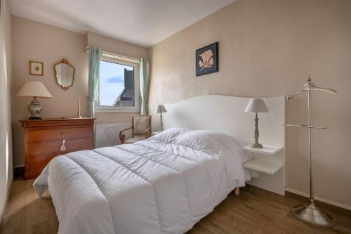 une chambre avec un lit blanc et une fenêtre dans l'établissement Appartement pour 4 - 300m du centre-ville, au Pouliguen
