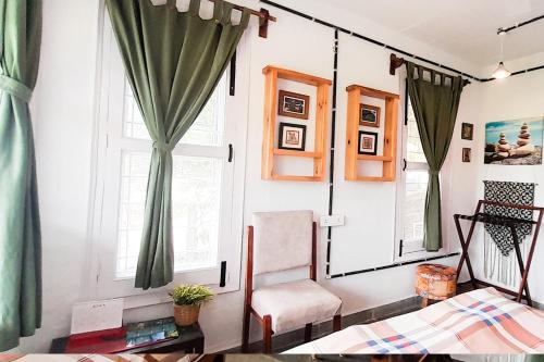 a living room with green curtains and a chair at Forest Side Farm - Homestay at Kotabagh Near Nainital and Jim Corbett in Kota Bāgh
