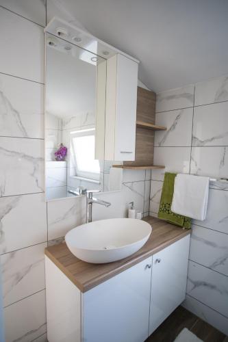 ein weißes Badezimmer mit einem Waschbecken und einem Spiegel in der Unterkunft Apartments Diva in Ston